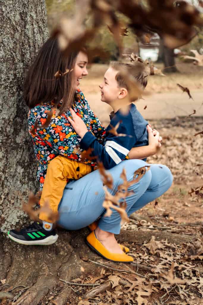 Mom and son laugh while fall leaves blow in Downtown Madison Alabama during a photoshoot with Andrea Angles Madison Al Family Photographer
