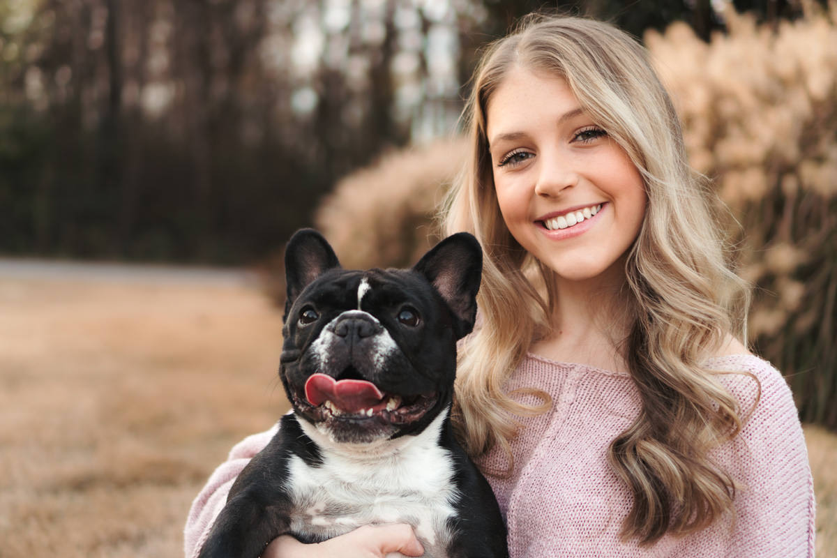 Girl in a pink sweater posing with her dog in a portrait photography session in Huntsville Alabama